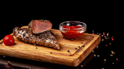 two juicy beef pepper steak with a air fryer medium rare, with a red sharp sauce on a wooden board, on a black background. Copy space