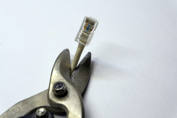 Scissors cut through a coaxial TV cable on white background .