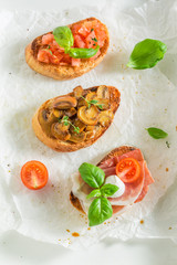 Mix of bruschetta with fresh ingredients on white table
