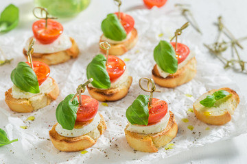 Crostini made with mozzarella and tomato on white paper