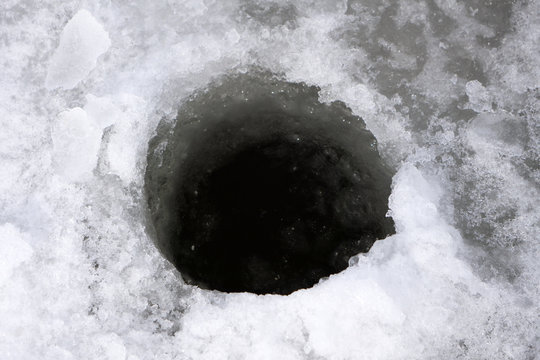 Ice-hole in ice on a pond left fishermen