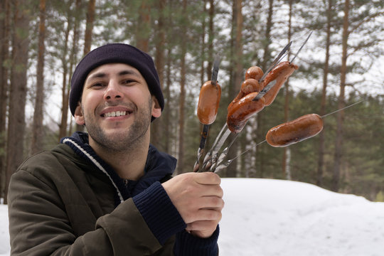 Man grilled sausages over firecamp.