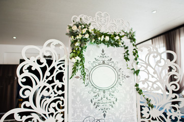 Special photo zone with small wooden wall decorated with flowers and wedding couple's initials.