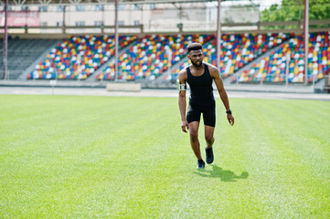 African american male athlete in sportswear doing jump exercise at stadium.