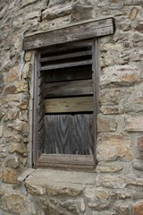 Fototapeta na wymiar Wood plank window on a very old round stone tower grist mill (windmill)
