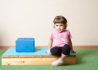 little girl, 3 years old. doing yoga with cubes