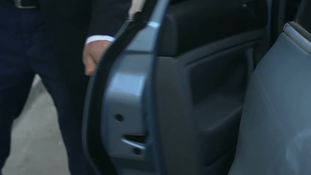 Personal chauffeur getting out of car and opening door to his boss, service