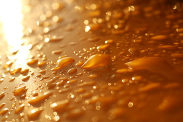 Water drops on a orange metal surface 