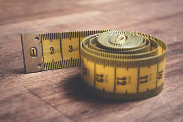 Macro Of A Rolled Up Yellow Measuring Tape On A Wooden Table
