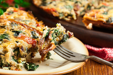 Portion of frittata made of eggs, mushrooms and spinach