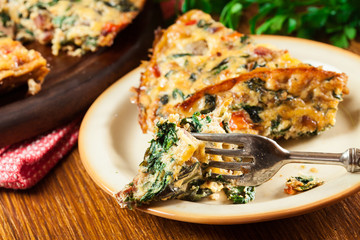 Portion of frittata made of eggs, mushrooms and spinach