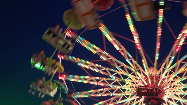 Colorated wheel rotate at the amusement park in the night