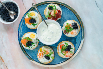 Selection of cocktail blinis with salmon, cured bresaola, crayfish, caviar, quail eggs and sour...