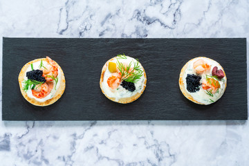 Cocktail blinis with crayfish, caviar and sour cream - gourmet party food - top view