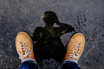Top View of Photogrpaher taking Self Portrait by Reflection Shadow on the Ground after stopped Raining