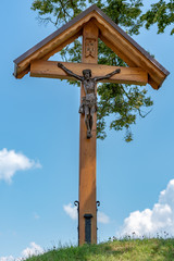 Flurkreuz mit Jesus vor blauem Himmel und Ästen - Kalvarienberg