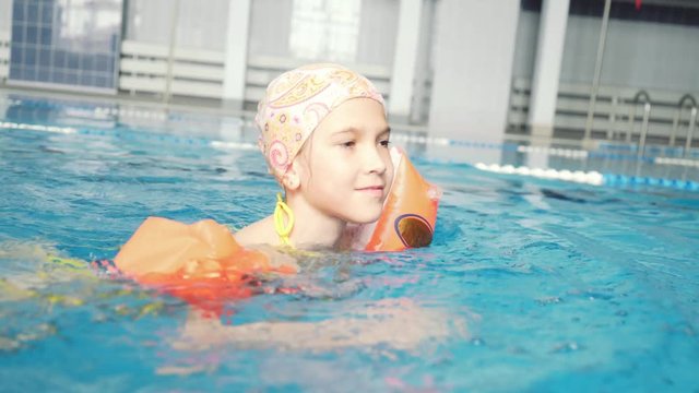a little girl in inflatable armlets floats in the pool. Bracers for swimming. The girl learns to swim.