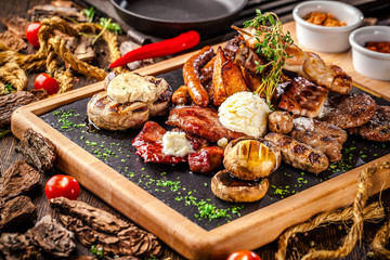 Arabian cuisine in Dubai. Assorted fried sausages on a grill, with sauce, on a wooden board. The concept is a beautiful serve in the restaurant. Background image.