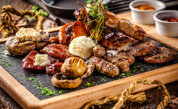 Arabian cuisine in Dubai. Assorted fried sausages on a grill, with sauce, on a wooden board. The concept is a beautiful serve in the restaurant. Background image.