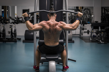 Hombre fuerte con grandes músculos entrenando jalón en el gimnasio. Ponerse en forma.