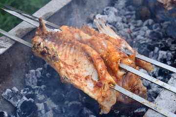barbecue marinated fish preparing on grill over charcoal in nature. BBQ grilling