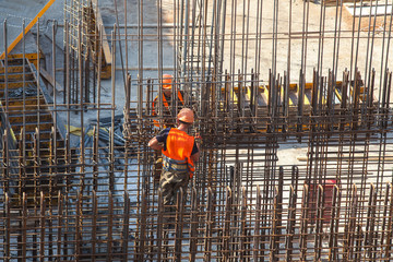 Fototapeta premium Construction of a large commercial building. Worker connects the armature at the construction site