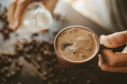 Man Pouring Milk In Steamed Coffee