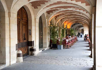 Fototapeta na wymiar Arkadengang mit Restaurant-Terrasse an der Place des Vosges, Stadtviertel Marais, Paris, Ile de France, Frankreich