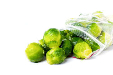 Plastic bag with frozen brussel sprouts isolated on white. Vegetable preservation