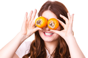 Woman holds persimmon kaki fruits on eyes, isolated