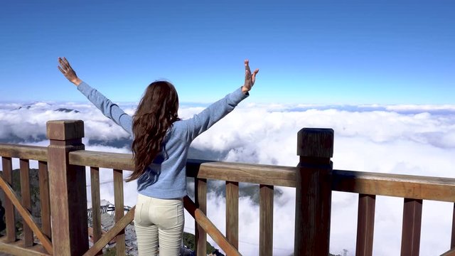 Woman raising hands, looking on landscape on Fansipan mountain in Sapa, Vietnam