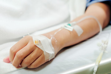 Close up image of IV drip in patient's hand in hospital.