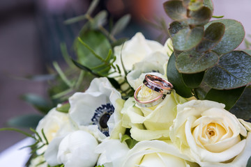 Bouquet of roses and rings lying on table