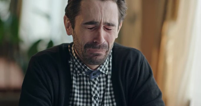 Miserable upset man sitting crying at a table