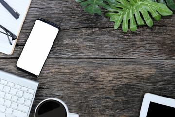 Smartphone white screen on wooden table and supplies with keyboard and coffee, Top view with copy space.