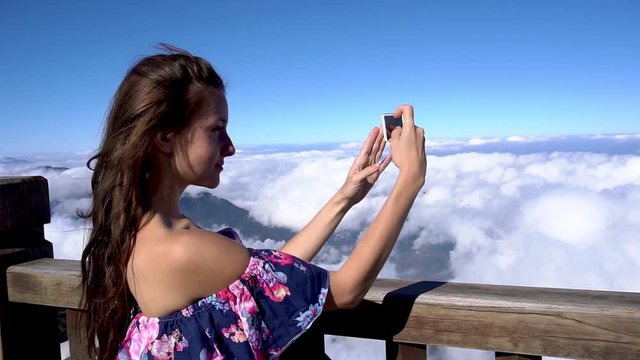 Travel concept. Woman making pictures on smartphone on Fansipan mountain in Sapa