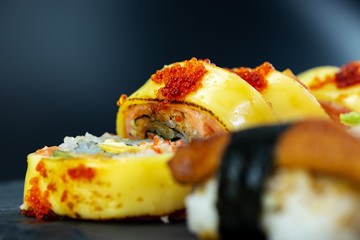 cheese and ebi eggs on top on Japanese sushi on black stone dish
