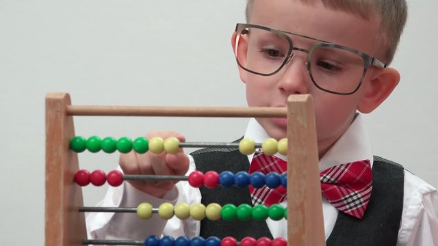 Portrait of funny little child with big eyeglasses numbering, wooden counting