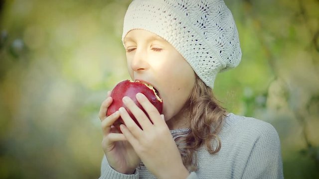 Portrait of a little girl who eats a red Apple in the Park