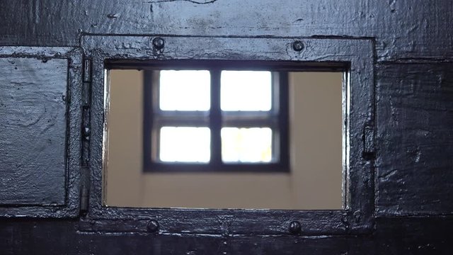 Detail of man hand opening prison window door, a look inside