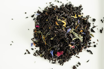 A mixture of dry leaves of black and green tea with flowers on a white background