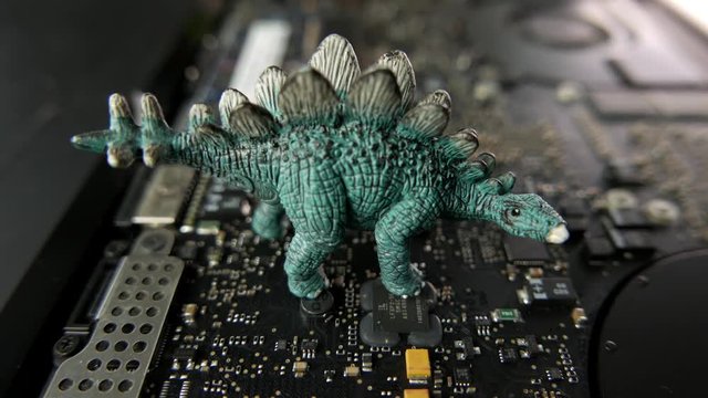 Dinosaur toy standing on circuit board. Dinosaur technology.
