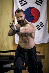 Hombre fuerte con grandes músculos entrenando artes marciales con arma han bo. Defensa personal...
