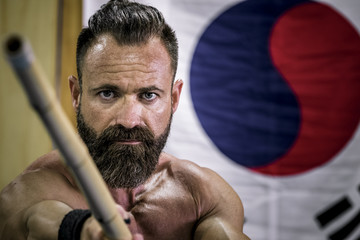 Hombre fuerte con grandes músculos entrenando artes marciales con arma han bo. Defensa personal...