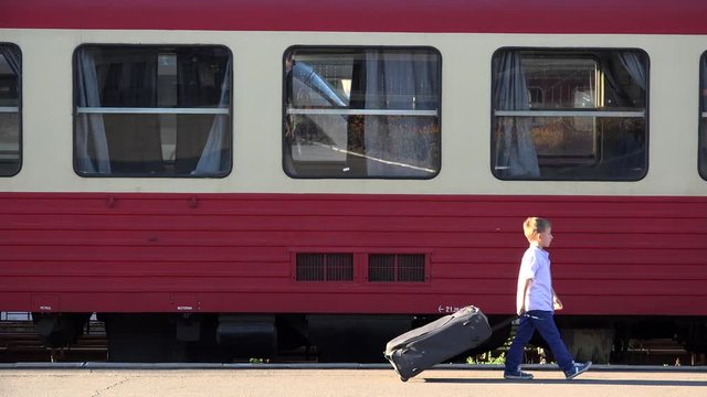 Little child with big luggage walk in train station, find his own way, confident