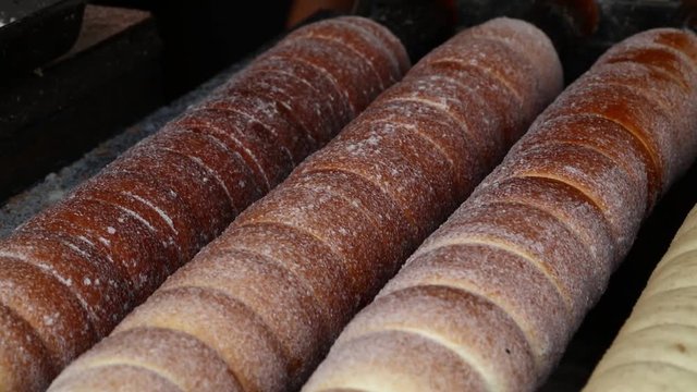 Close up sweet Trdelnik baking on grill and rolling, this spit cake is popular in Europe, Austria, Hungary, Slovakia and Czech, especially in Prague