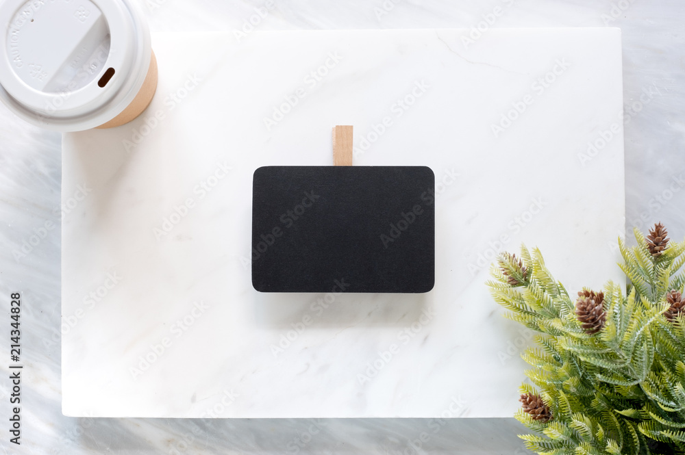 Poster Top view of Clip blackboard,pine leaf and coffee cup on white marble block and stack on grey marble table.Flat lay Mock up template for adding or display text or design.Stationery item.