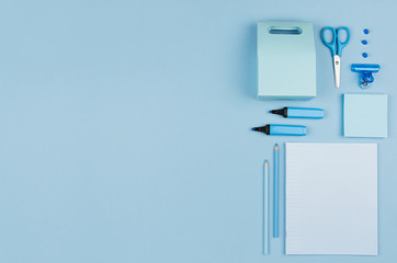 Modern youth workplace - neon blue stationery as decorative border on blue background, top view.