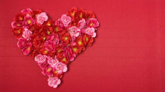 Sobre fondo rojo aparece un corazon de flores.