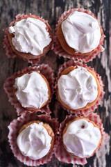 Cupcakes with white cream on a wooden background